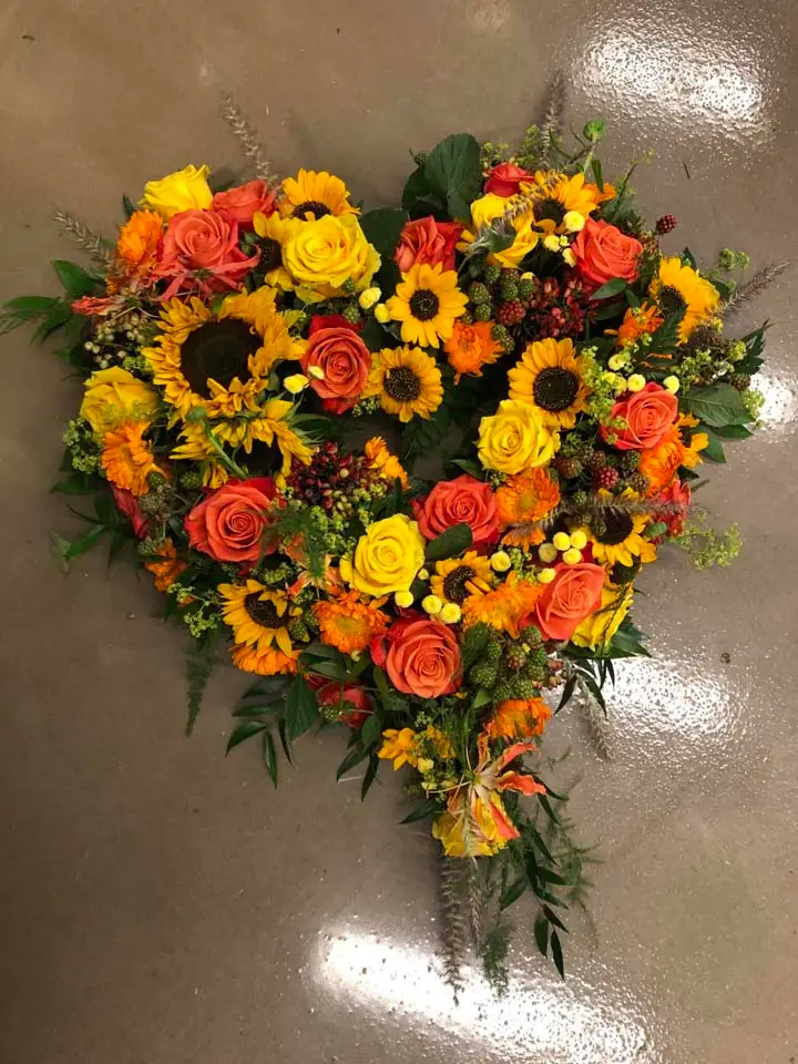 Hjerte af solsikker og orange blomster