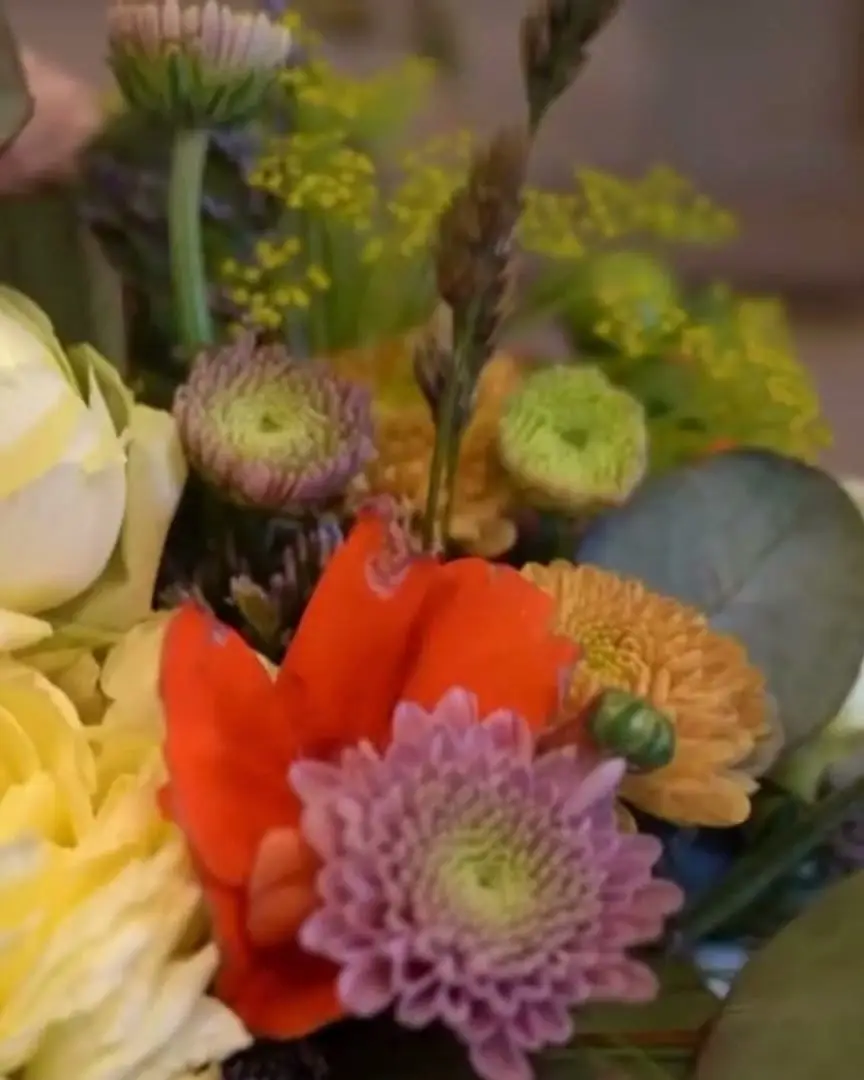 Buket med cremefarvede roser og orange blomster